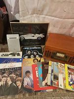 Various vinyl records including The Beatles, Lionel Richie, The Nylons, Al Stewart, Blues, and a white Phillips speaker with vintage Lamborghini glass-framed photo behind.