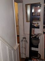 Tall black IKEA Lack floating shelf with multiple shelves displayed in a hallway corner.