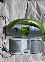 Overhead view of the two clock radio speakers showing the green Imode unit on top with a curved design and the white Emerson unit below with dual speaker grilles and a central docking station.