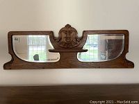 Full frontal view of entire carved oak mirror panel mounted on wall