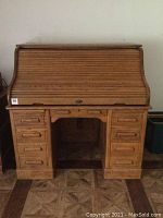 Front view of antique roll top oak desk with tambour roll-top closed, showing two pedestal bases with 8 drawers and central knee space.