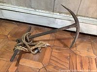 Anchor angled on wood parquet floor showing flukes and rope