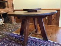 Side view of the wooden round dining table showing carved legs and base.