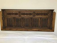 Full view of carved wooden panel mounted above bed