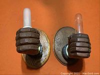 Front view of two wall sconces, one with frosted bulb and one with clear bulb, placed side by side on orange surface