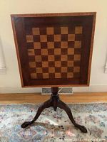 Full-frontal view of the table in tilt position showing inlaid chess/checkers board and pedestal base