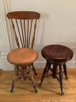 Two wooden swivel piano stools, one with a chair back and one without, both with claw feet with glass ball details.