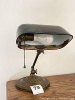 Full side view of lamp showing green shade, adjustable arm, ornate brass base and numbered sticker.