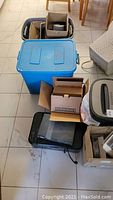 View of various items including Canon printer, plastic boxes, cardboard boxes, and a CRT monitor.