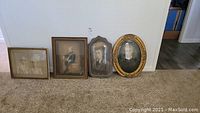 All four vintage framed portraits displayed against a wall, showing differences in frame styles and sizes