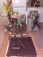 Full lot overview showing dog bed, faux flowers, figurine, folded chairs, cushions, gardening books, and table parts.