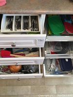 Drawer with additional flatware spoons and forks, close-up of detailed handle designs.