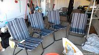 Four folding patio chairs with metal frames and vertical striped cushions in a garage setting.
