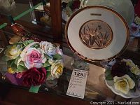 Display of porcelain items including Royal Doulton roses, Beswick pheasant, Radnor porcelain piece, and Chokin decorative plate with gold trim.