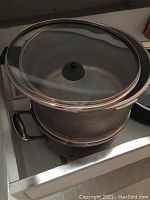Photo of stainless steel pot with glass lid showing metal handles.