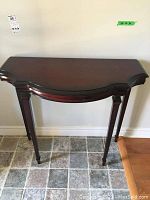 Front view of the dark wood demilune table showing curved front and straight back against wall