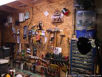 Wide view of OSB pegboard wall with assorted hand tools mounted