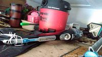 Photo of the red and black 10 gallon Shop-Vac with the Rowenta Delta Force Extreme handheld vacuum cleaner in front laying horizontally.