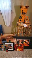 Full view of bamboo end table with ceramic decor items on top, framed and unframed photography prints leaning against table and bamboo magazine rack to left