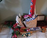 Overview of the wrapping paper rolls, gift bags, wooden puzzle box, poinsettia garland, and red ornament storage box with dividers.