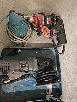 Photo of Makita hand sander, Porter Cable random orbit sander, and other tools on a blue surface