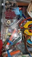 Photo of clear plastic compartment organizer with various beads, jewelry findings like clasps, and pliers scattered below