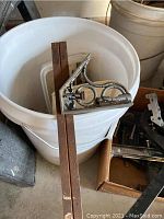 Carpenter's square with rust on metal parts and brown wooden handle resting on white bucket