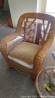 Wicker rocking chair showing front with beige cushion and patterned pillow