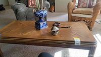 Photo of the oak coffee table with items on top including a blue art vase, ceramic skull figurine, and black key-shaped ornament.