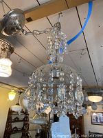 Pendant ceiling light fixture with hanging glass crystal beads and silver-tone metal chain and base attached to ceiling.