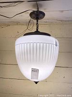 Front view showing ribbed white glass globe shade and antique bronze metal canopy and chain suspension.