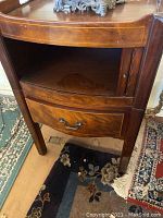 Front view of wooden side table showing drawer, tambour door shelf, and damage on top finish.