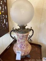 Front view of vintage table lamp with frosted glass globe and floral vase base showing overall condition and design