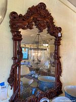 Front view of ornate carved wooden frame mirror, highlighting overall design and bevelled glass