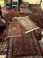 Overall view of four small rugs on top of large red oriental runner