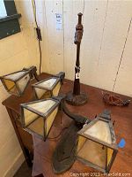 Overview of two wall sconces and table lamp on wooden table, four slag glass shades visible