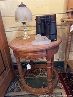 Side table with lamp placed on top, also showing binoculars and glass lion figurine (not included).