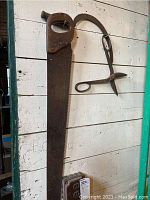 Large vintage hand saw and a curved gardening or farming blade hanging on a wall