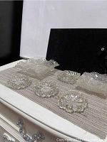 Photo of small square baskets, ashtrays and butter dishes arranged on a surface