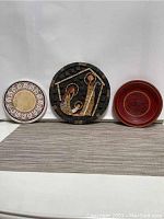 Full view of trio: religious mosaic, Pfaltzgraff trivet, and small red wooden bowl