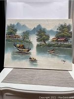 Full front view of the oil on canvas Asian river scene painting, showing boats on the water, homes, trees, and mountains, signed Tay.