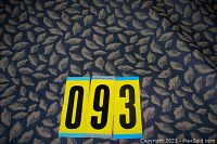 Close-up of fabric surface showing beige leaf motif over blue background with auction lot number 093