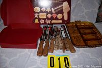 Silicone bakeware, steak cutters, carving knife, and Wearever Super Shooter with original box arranged on cloth