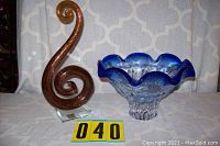 Photo showing the Murano glass spiral piece with amber coloring on clear glass base, and the blue wavy rim glass bowl side by side on a table.