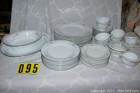 Full view of Noritake dinnerware set laid out showing plates in stacks, cups, saucers, sugar bowl with cover, and creamer on light background.
