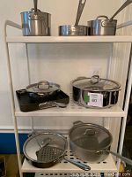 Three saucepans on top shelf, each with handle and two with lids visible