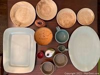 Wide arrangement showing the full collection of ceramics on a wooden table including plates, bowls, pitchers, mugs, and serving pieces