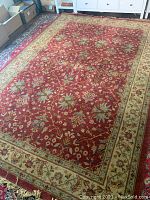 Full view of carpet showing red field, ivory border and overall pattern