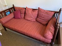 Full view of the daybed showing red striped cushions and pillows on solid wood frame.