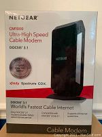Front view of Netgear CM1000 cable modem box showing device image and key specs including DOCSIS 3.1, gigabit speed, and compatible providers.